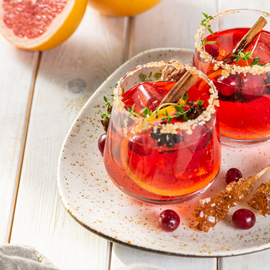 Reddish orange drinks in stemless wine glass with garnish