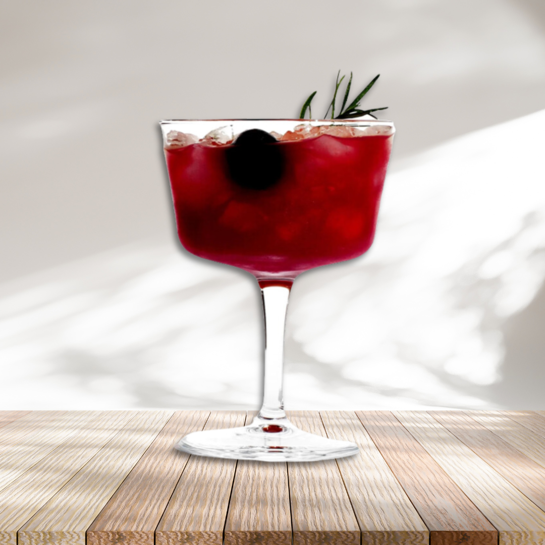 Red drink in glass garnished with rosemary and a cherry