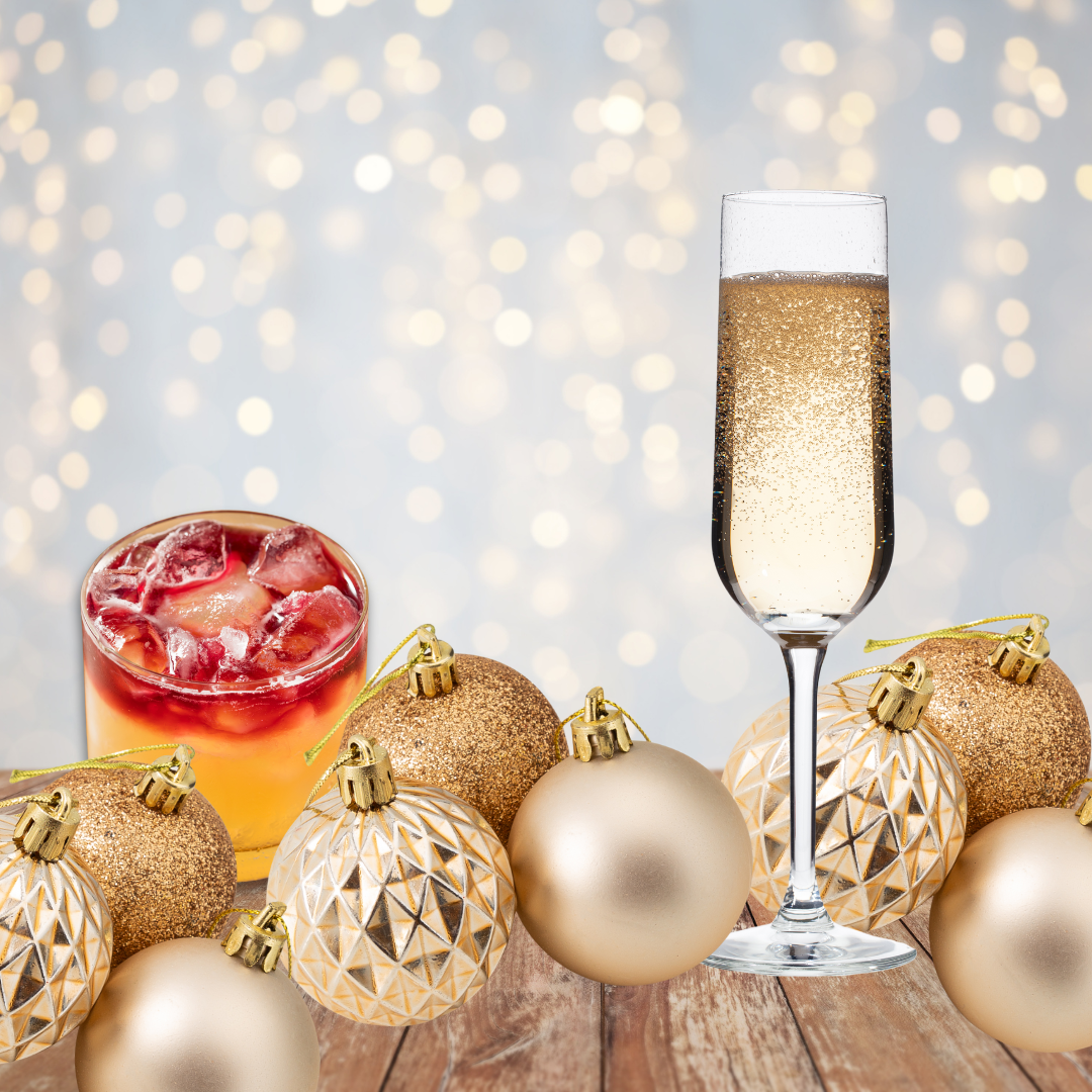 flute with bubbly liquid, old fashion glass with orange liquid, ice and topped with red. Gold ornaments in foreground and white lights in background.